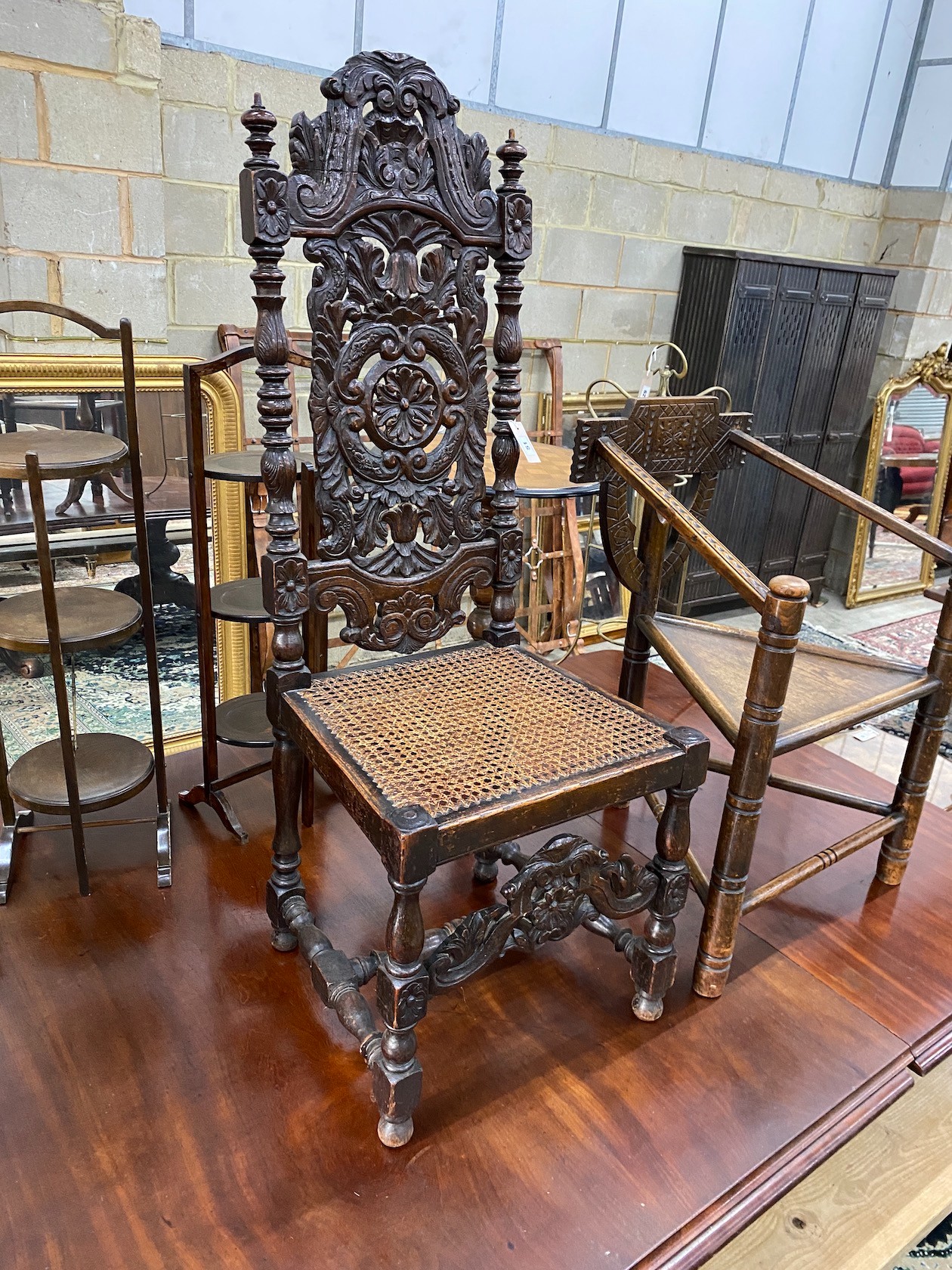 A Carolean style carved oak cane seat highback dining chair together with a chip carved oak chair with triangular seat